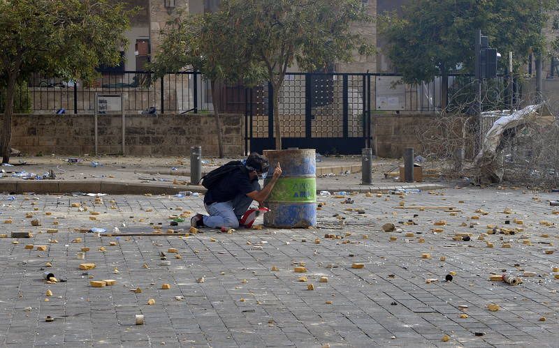 Un manifestante se protege tras un bidón