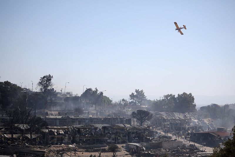Un avión de bomberos vuela sobre los refugios destruidos