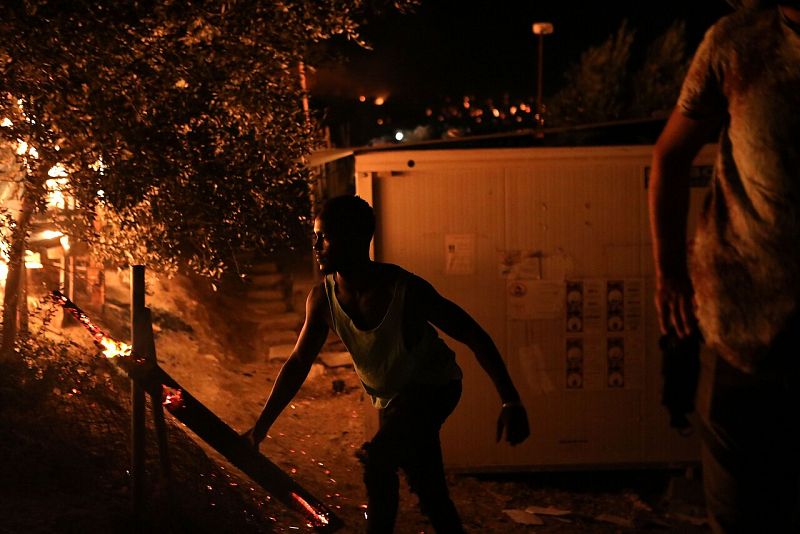 Un migrante mueve un tronco ardiendo en el campamento de Moria