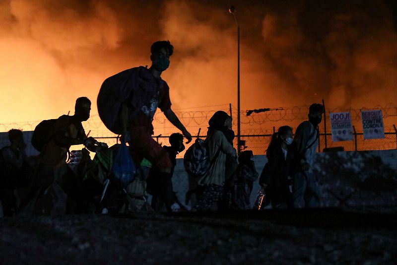 Refugiados cargan sus pertenencias mientras huyen del fuego