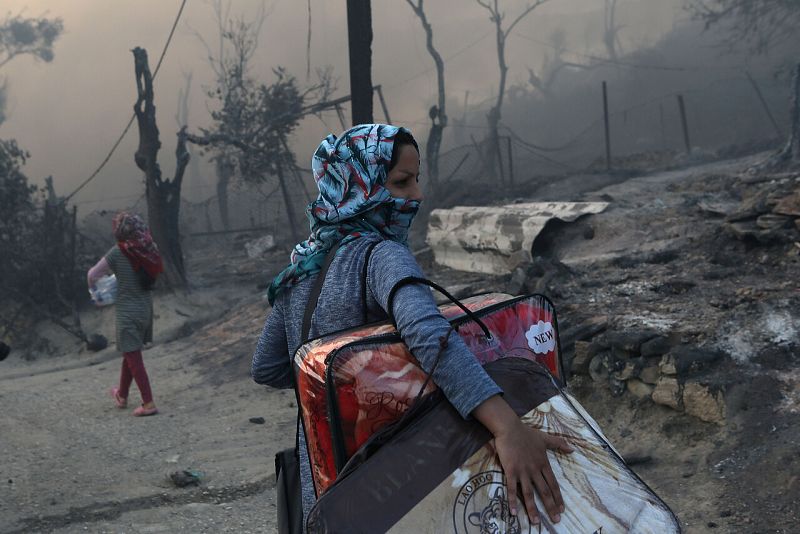 Una mujer lleva sus pertenencias tras el incendio