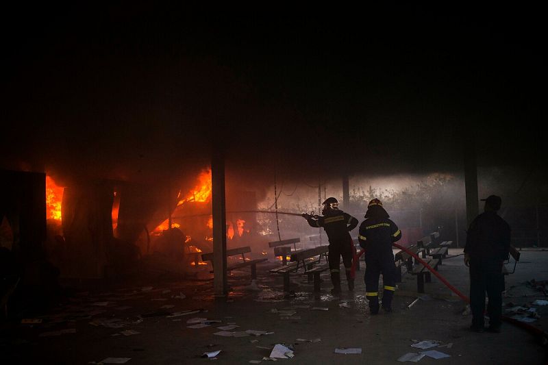 Los bomberos tratan de extinguir un incendio con una manguera 