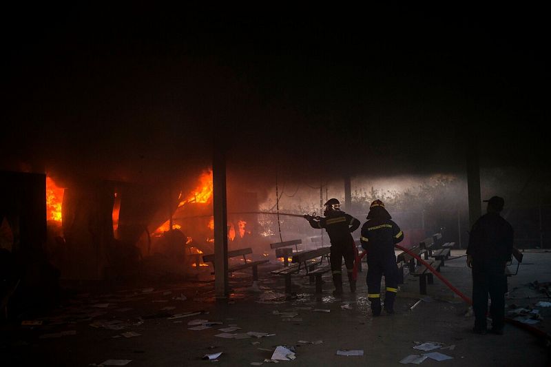 Los bomberos tratan de extinguir un incendio con una manguera