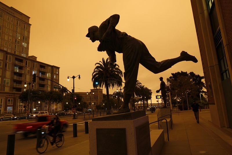 Un cielo naranja a primera hora de la tarde y detrás, una estatua de un lanzador de beisbol de los Gigantes de San Francisco, Gaylord Perry en Oracle Park.