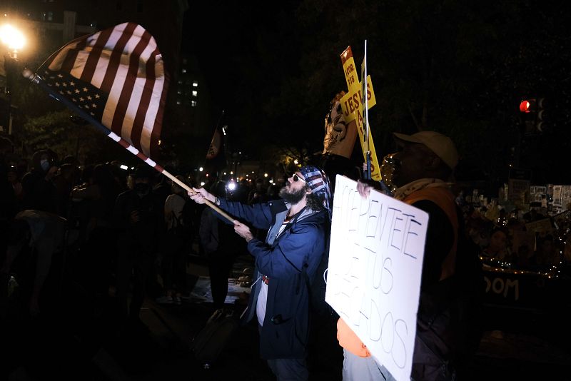 Un hombre agita una bandera norteamericana, durante la noche de las elecciones, en unas protestas en Washington DC
