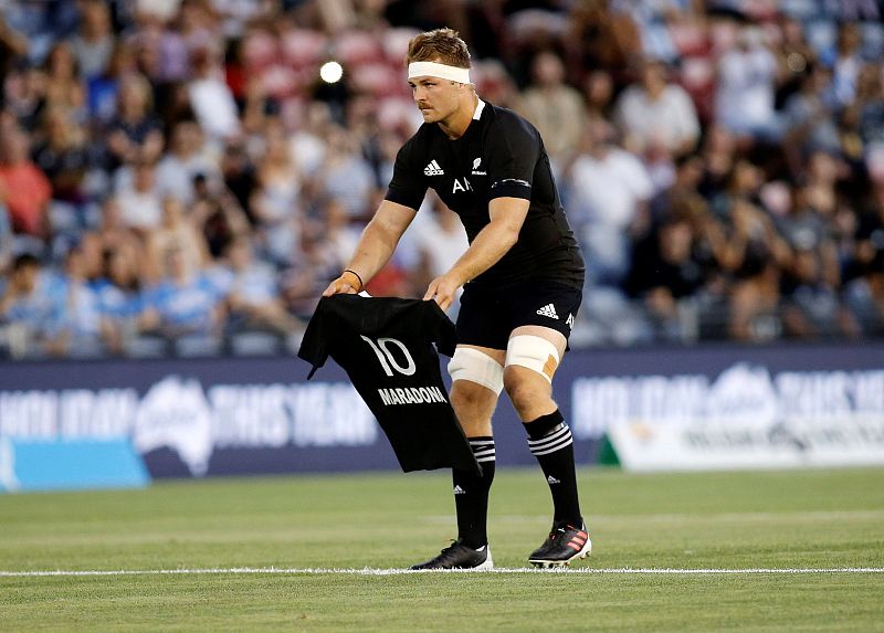 Un jugador de los All Blacks posa una camiseta del equipo dedicada a Maradona en el centro del campo antes del partido ante Argentina