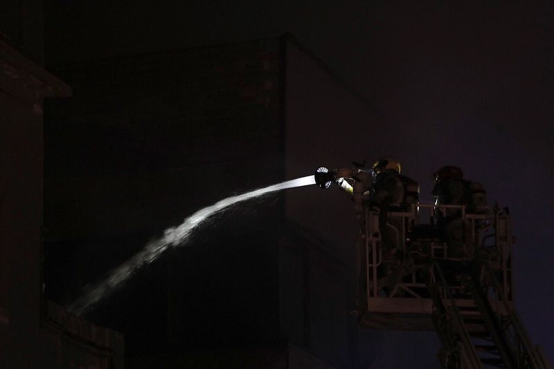 Un bombero intenta apagar el incendio en la nave ocupada de Badalona