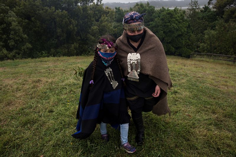 Una madre y su hija pertenecientes a la comunidad Mateo Nahuelpán, del pueblo originario mapuche, caminan en un prado antes de que se visibilice el eclipse solar en Monkul, en la región de la Araucanía.