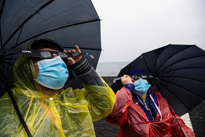 Las malas condiciones climatológicas no ha echado atrás a los turistas y residentes que esperaban contemplar el eclipse, por lo que se ha pertrechado con chubasqueros y paraguas para poder verlo.