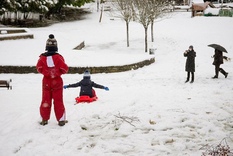 Un manto de nieve también ha cubierto Vitoria. En la imagen, unos niños juegan a deslizarse en trineo por una pendiente en un parque en de la ciudad.