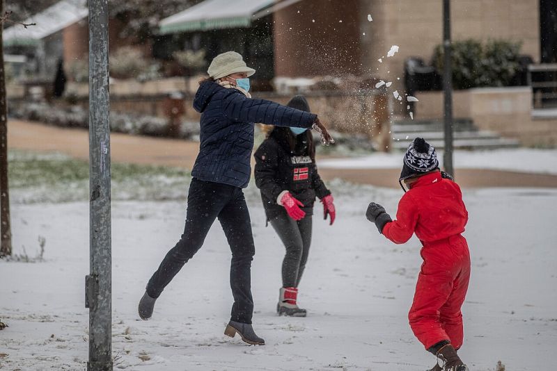 Una mujer y unas niñas juegan con la nieve en Madrid