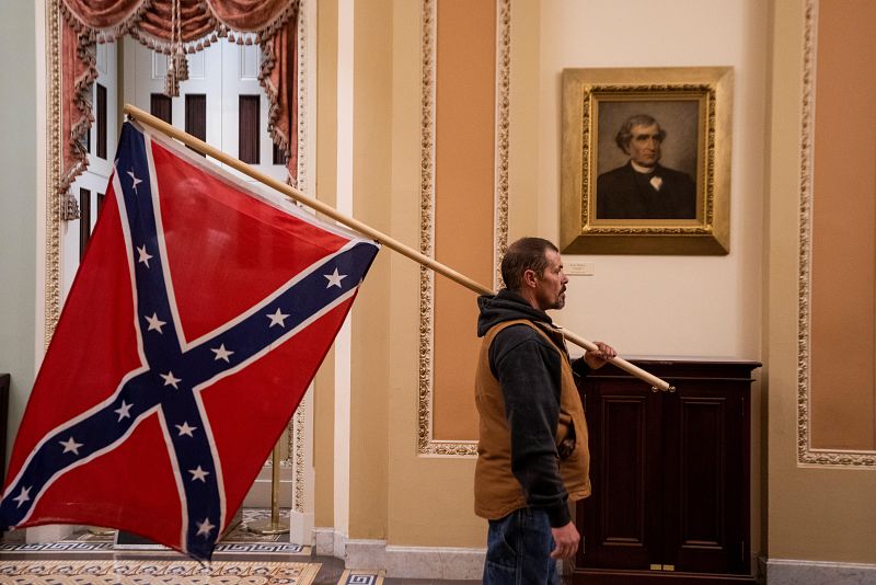 Un asaltante pasea con la bandera confederada por el vestíbulo del Capitolio