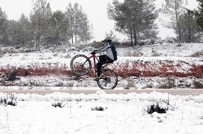 Un ciclista levanta la rueda delantera en una calzada nevada