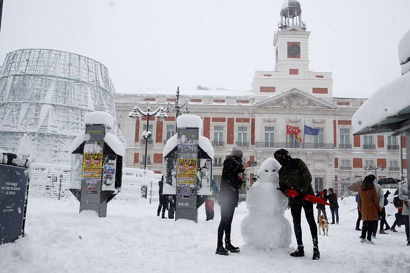 Una pareja hace un muñeco de nieve en la Puerta del Sol en Madrid.