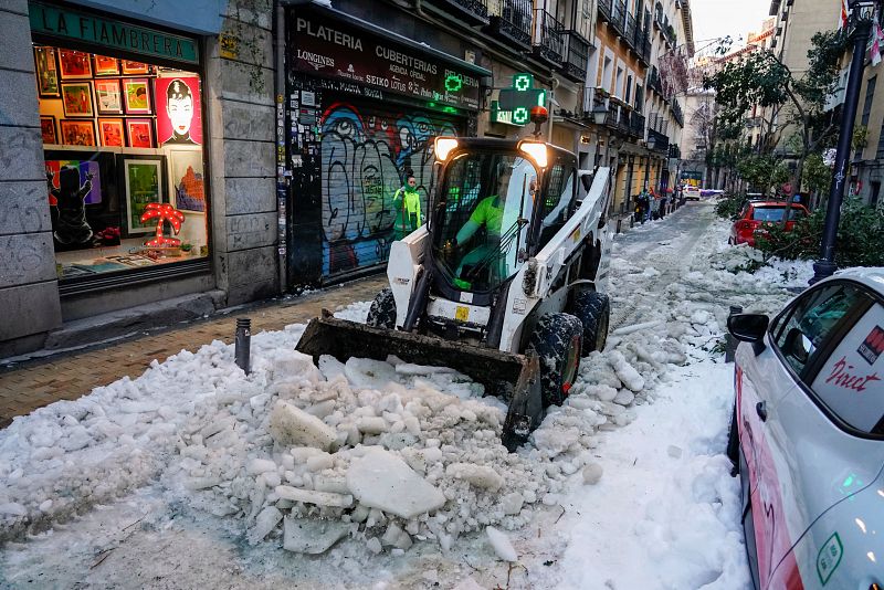 Una excavadora limpia de nieve y ramas una calle del centro de Madrid