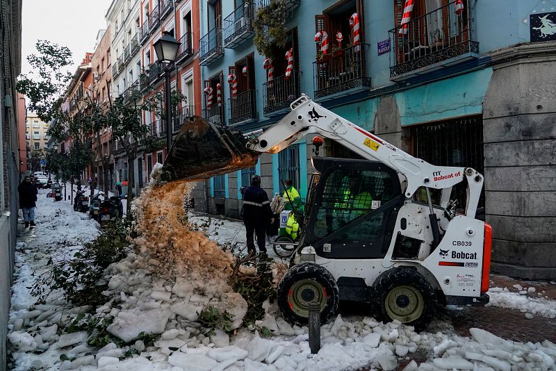 Una excavadora limpia de nieve y ramas una calle del centro de Madrid