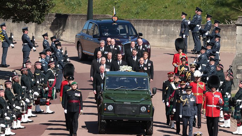 El vehículo con los restos del duque de Edimburgo, seguido por sus hijos y nietos y, al fondo, Isabel II a bordo del Bentley real, llegan a la capilla de San Jorge.