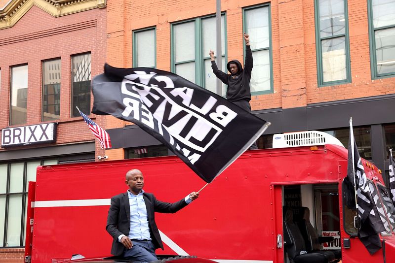 Un hombre ondea una bandera con el lema Black Lives Matter