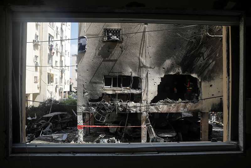 Parte de un edificio residencial dañado se ve a través del marco de una ventana después de que un cohete golpeara el edificio en Petah Tikva, Israel.