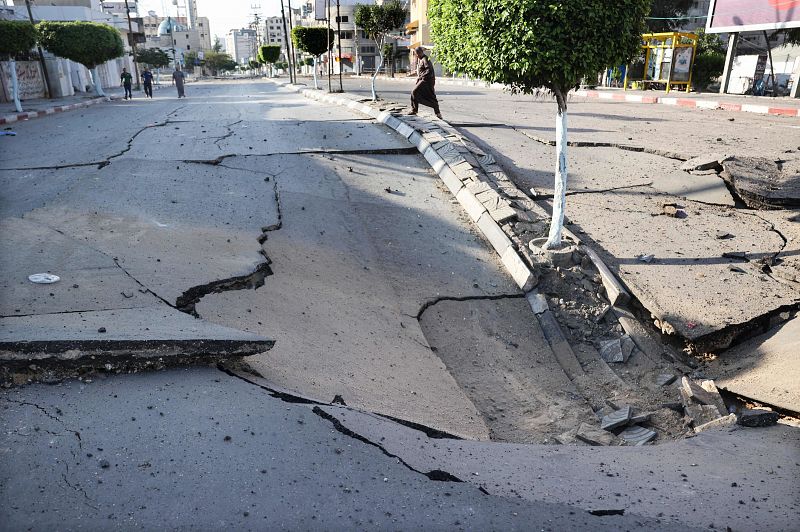 Palestinos caminan alrededor de un enorme cráter en una carretera principal en la ciudad de Gaza controlada por Hamas.