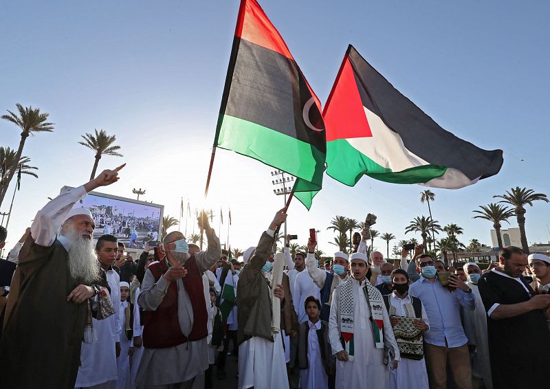 Fieles musulmanes libios levantan una bandera palestina en solidaridad con Gaza y Cisjordania, mientras se reúnen para realizar las oraciones en la Plaza de los Mártires de la capital, Trípoli.