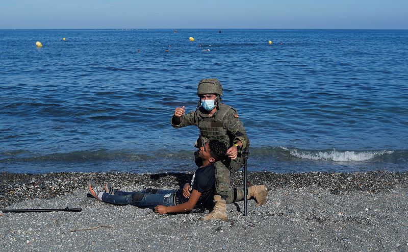 Un soldado español ayuda a un migrante marroquí que ha llegado exhausto a nado