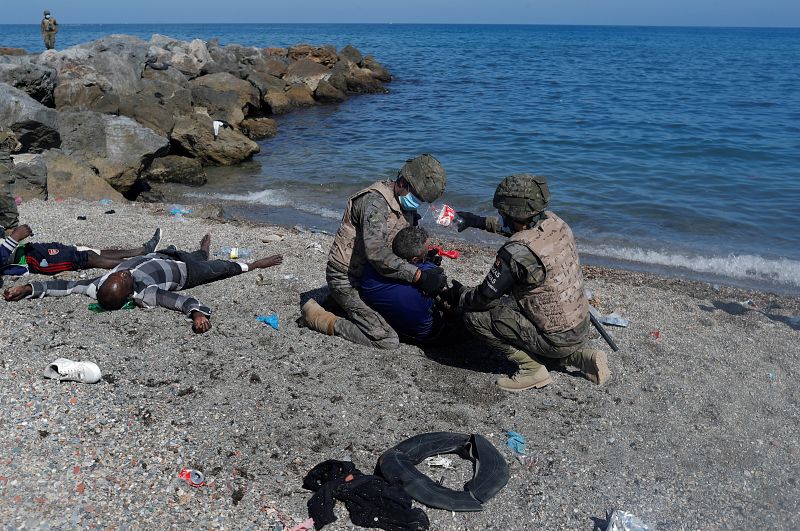 Dos legionarios españoles socorren a varios migrantes subsaharianos que acaban de llegar a Ceuta