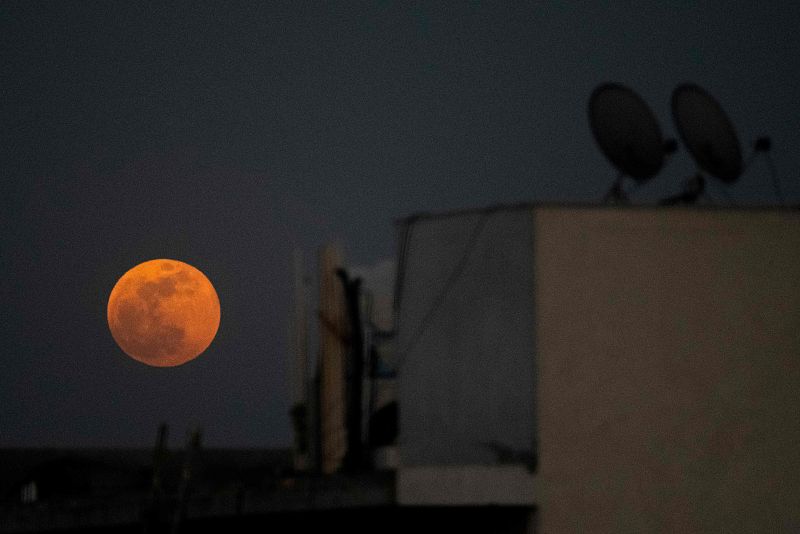 El astro se eleva sobre una zona residencial en Nueva Delhi durante un eclipse lunar.