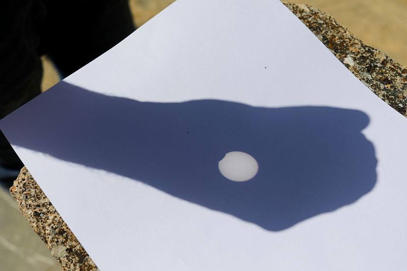 Un hombre utiliza un monocular para ver el reflejo del eclipse parcial de Sol, en Ronda, Málaga.