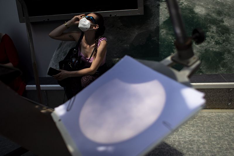 Una mujer observa el eclipse solar parcial con unas gafas especiales y un telescopio, en el observatorio astronómico de Praga.