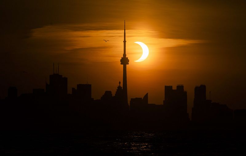 El eclipse de Sol, recortado sobre el 'skyline' de Toronto, en el que destaca la Canadian National Tower.