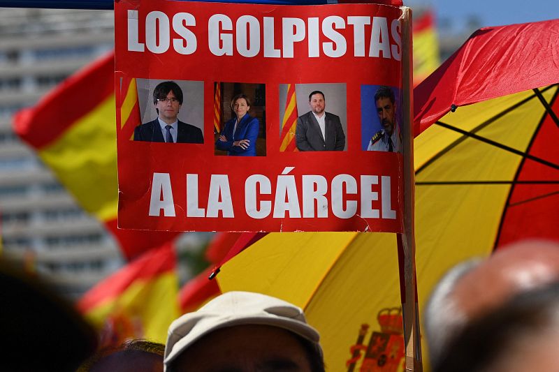 Un asistente a la manifestación en la plaza de Colón sostiene una pancarta en la que se lee "Los golpistas a la cárcel"