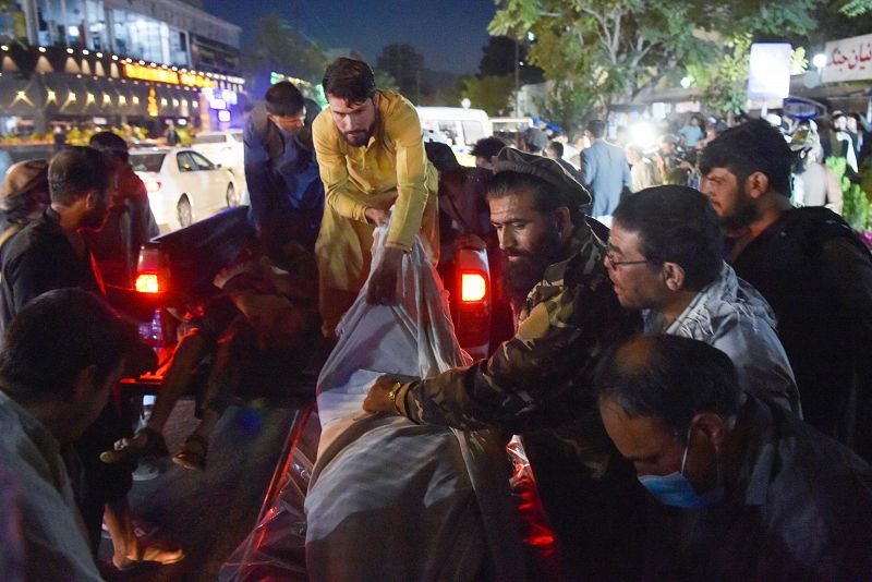 Voluntarios y sanitarios descargan cuerpos sin vida de una camioneta junto a un hospital.