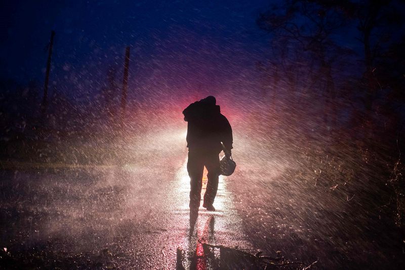 El jefe de bomberos de Montegut, Toby Henry, regresa a su camión de bomberos bajo la lluvia mientras los bomberos cortan los árboles en la carretera en Bourg, Luisiana