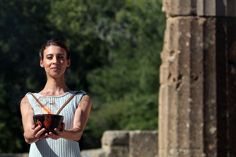 Una intérprete sostiene un caldero y la llama durante la ceremonia