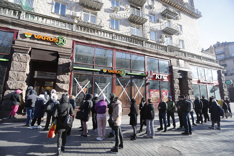 Un grupo de gente espera para poder entrar a una tienda de comida en Kiev