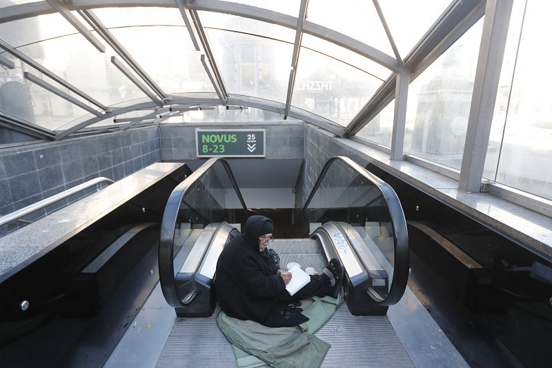 Una mujer sentada en las escaleras de entrada a un paso subterráneo en Kiev