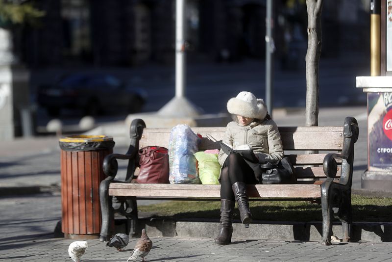 Una mujer lee sentada en un banco en el centro de Kiev