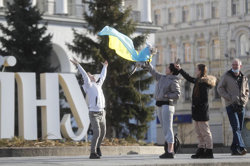 Un grupo de personas fotografía a un gato envuelto en la bandera de Ucrania en el centro de Kiev
