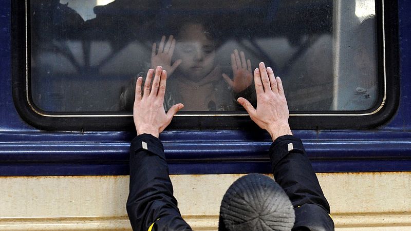 Un hombre se despide de un niño frente a un tren de evacuación en la estación central de trenes de Kiev