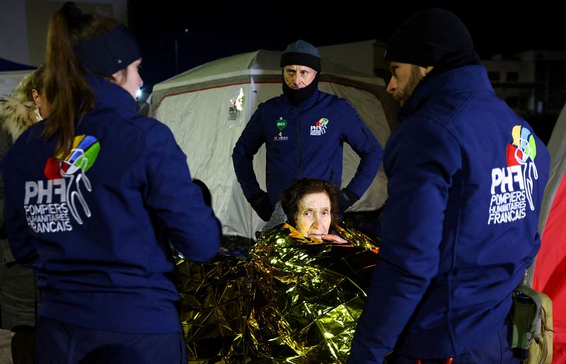 Personal humanitario de una ONG francesa arropa a una mujer y le brinda asistencia en la frontera de Ucrania con Polonia, en la ciudada de Medyka