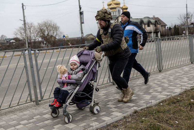 Un militar ucraniano ayuda a evacuar a una niña de la ciudad de Irpin, cerca de la capital, Kiev, por la única vía de escape que utilizan sus residentes