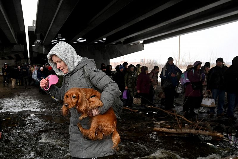 Los evacuados de Irpin atraviesan un puente destruido por los ataques de las fuerzas rusas. En la imagen, una mujer lleva un perro en sus brazos