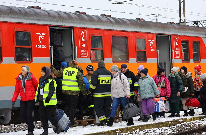 Voluntarios y efectivos del ejército polaco ayudan los civiles que llegan a Polonia para coger un tren en dirección a Cracovia. 