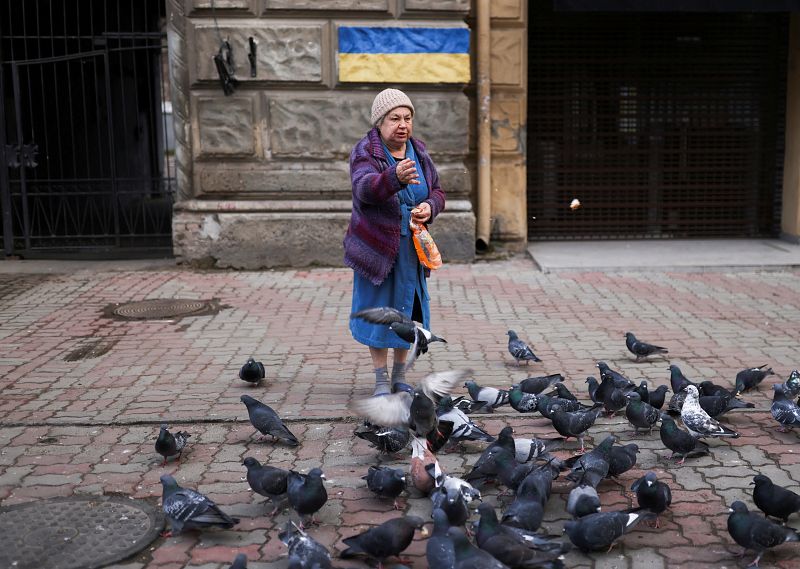 Una mujer da de comer pan a las palomas delante de su casa en Odesa, el puerto principal de Ucrania, uno de los objetivos de Rusia en el frente sur de la guerra