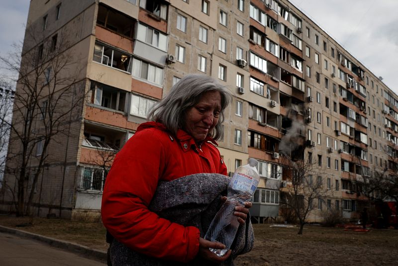 Una mujer se aleja de su casa que ha sido alcanzada este lunes, 14 de marzo por un proyectil de Rusia en el distrito de Obolon