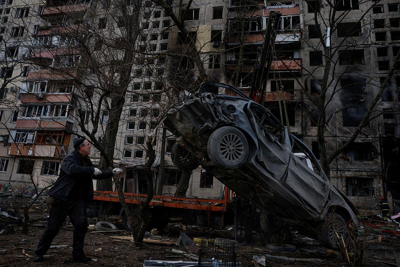 Un hombre ayuda a retirar un vehículo destruido por el ataque de las fueras rusas en el distrito de Obolon, en Kiev, donde continúa el ataque. Por la capital ucraniana pasa uno de los corredores humanitarios que se han abierto para evacuar civiles