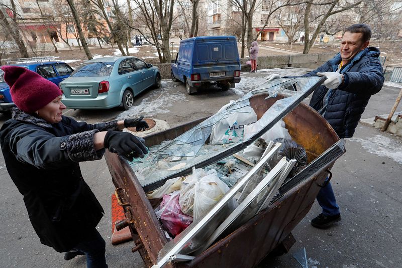 People remove debris from a residential building damaged by shelling in Makeyevka