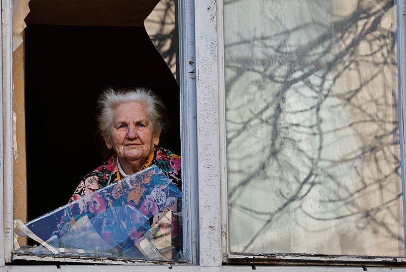 Una mujer mira a través del cristal de una vivienda destrozada por los bombardeos en Kiev, donde este miércoles siguen los bombardeos. 