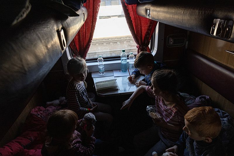 Niños huérfanos que huyeron de la ciudad ucraniana de Polohi, ocupada por el ejército ruso, esperan en un tren de evacuación antes de partir hacia la parte occidental de Ucrania, en la estación de tren de Zaporiyia, al sureste de Ucrania.
